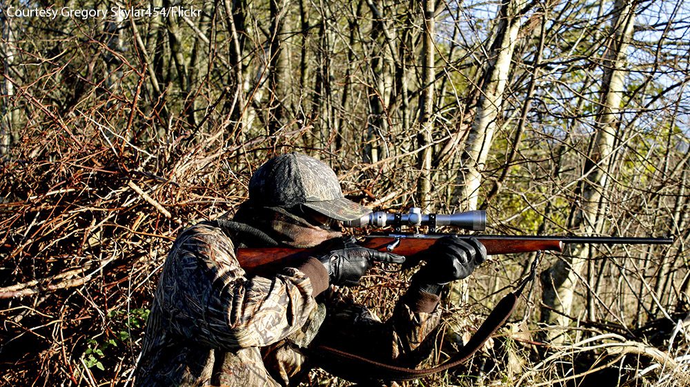 Person in camouflage shooting a rifle.