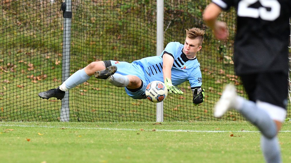 Male soccer player kicking soccer ball.