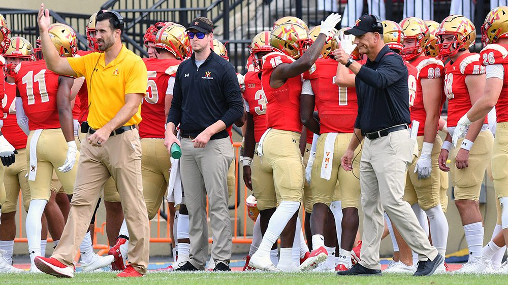 coaches and football players on sidelines