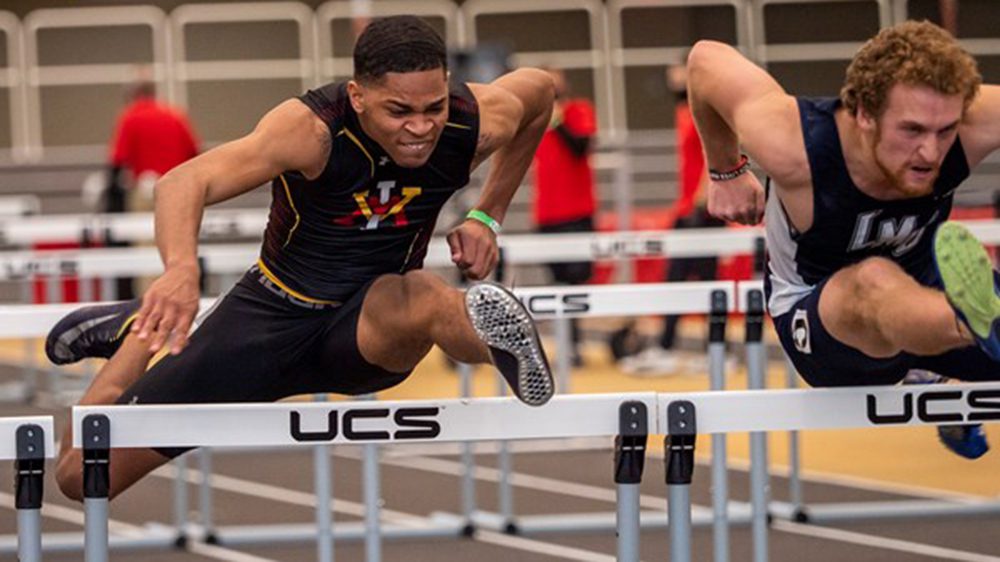 two track and field athletes jumping hurdles