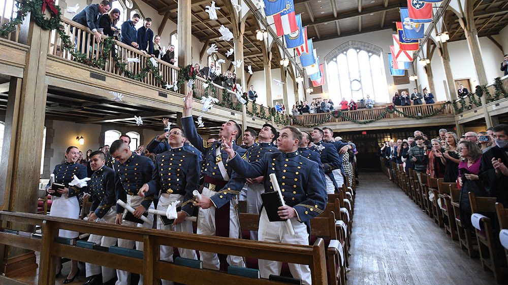 Cadets throw gloves in the air in Memorial Hall after graduation ceremony