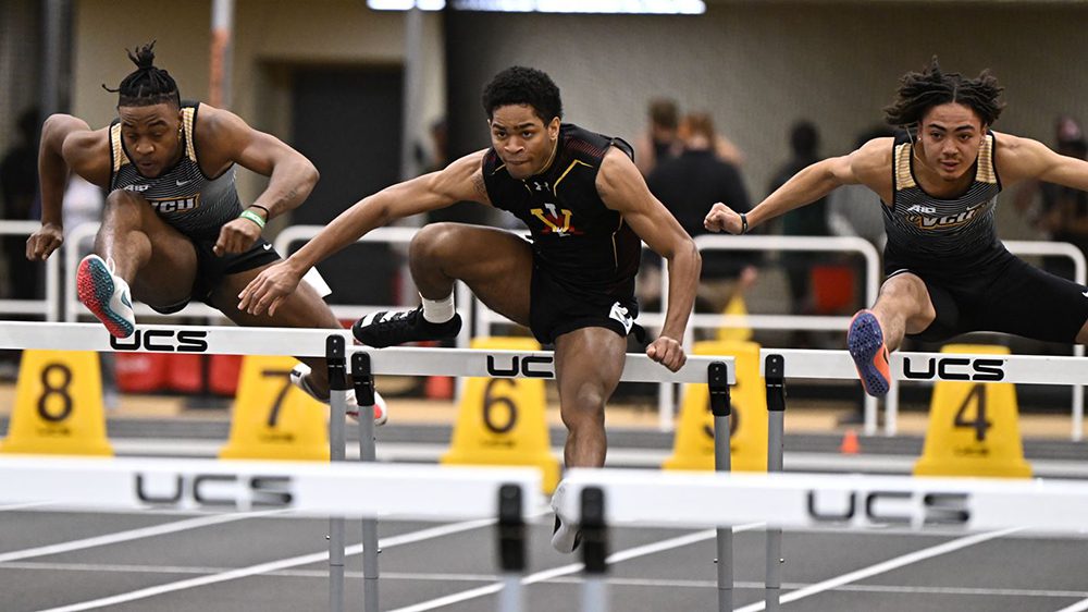 three track athletes jumping over hurdles