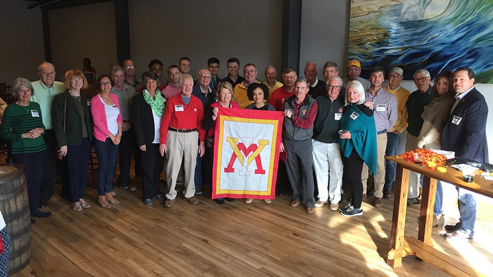 group of people posing with VMI flag, smiling