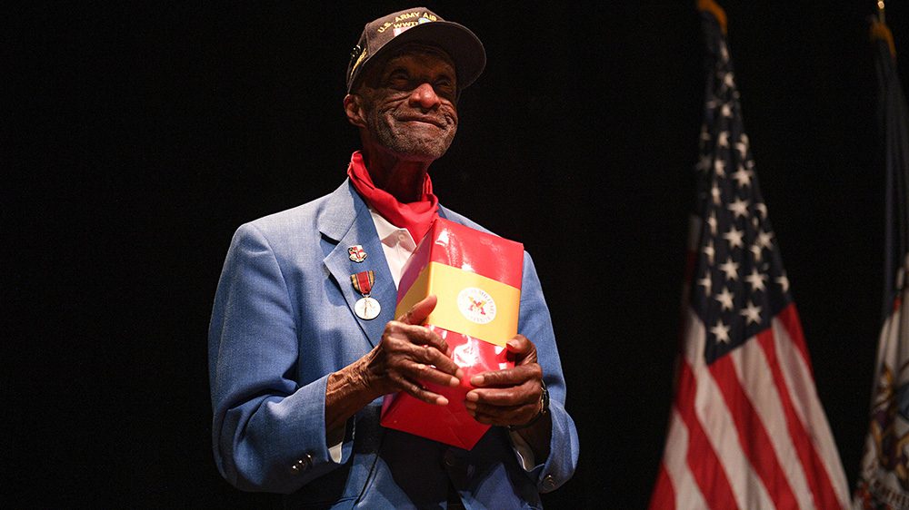 Man stands holding a gift, smiling