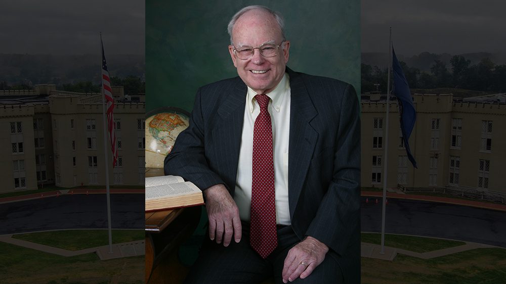 John B. Payne III ’58 smiling at a desk.