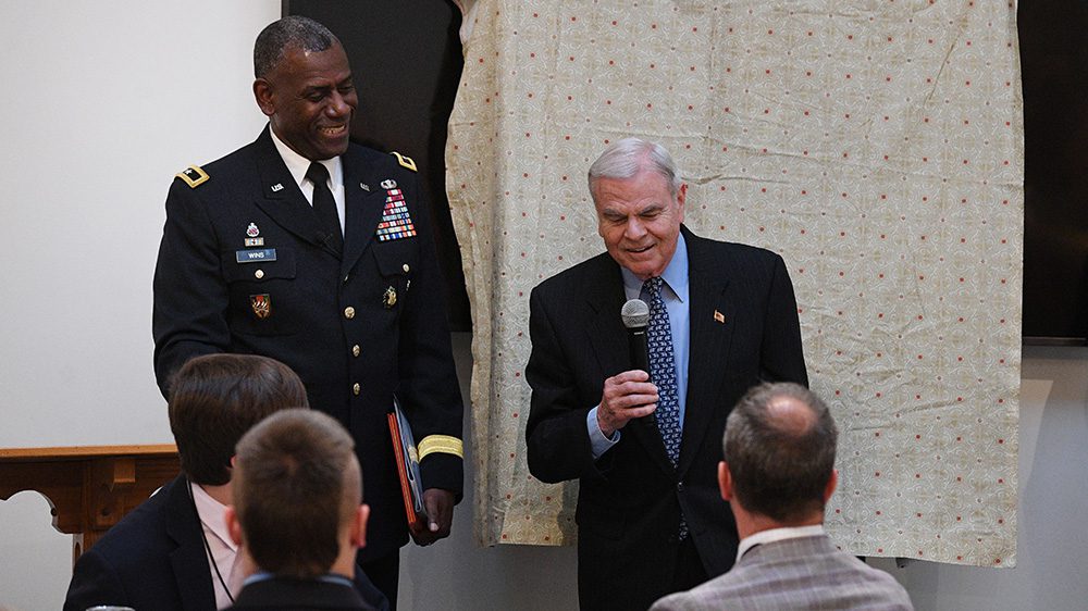 One man speaking while another looks at speaker