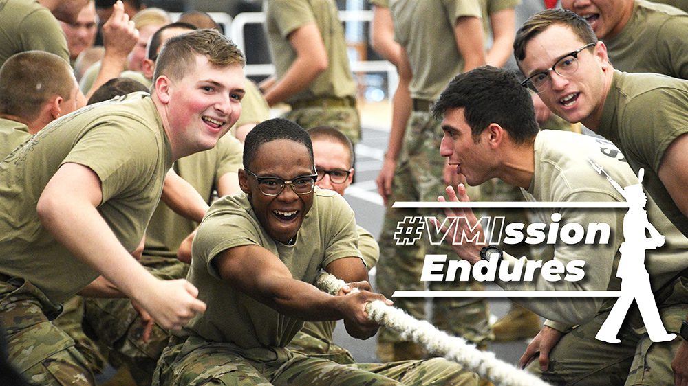 A cadet participates in tug-of-war while his brother rats cheer him on.