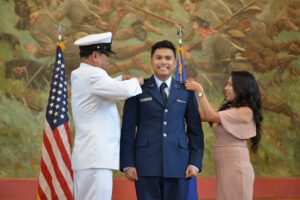 Ellis Orquiza ’22 smiling as he receives his shoulder boards from his family.