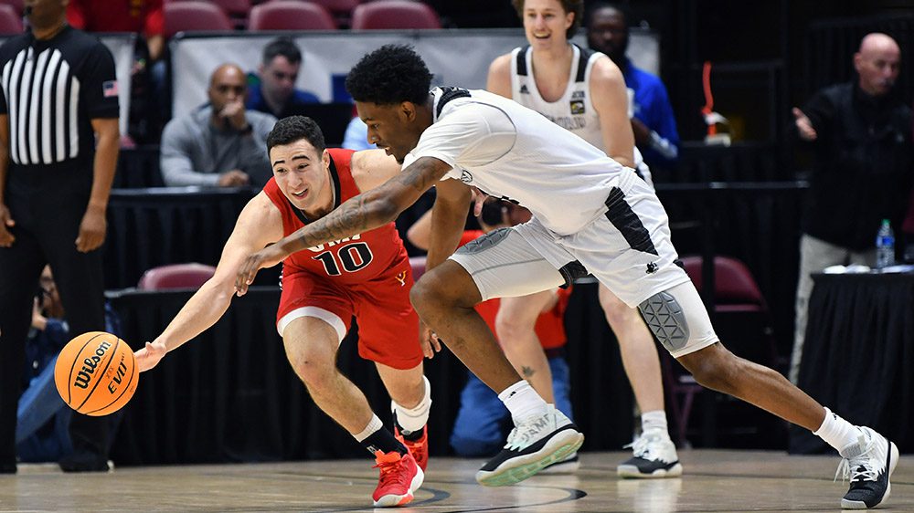 Two basketball players reaching for basketball during a game.