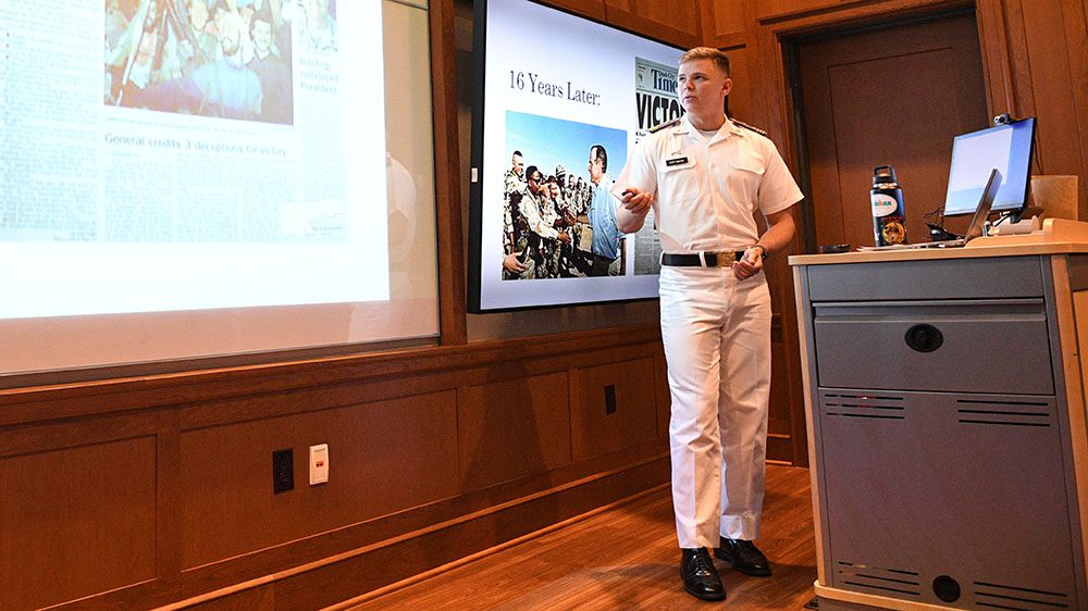 Cadet Michael M. Hoffmann ’22 stands in front of projector to present his thesis, “Kicking the Army’s Vietnam Syndrome: The Cultural Renaissance of the Post-Vietnam Army.”
