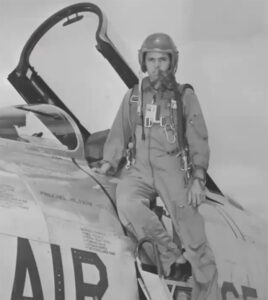 Col. Thomas H. Kirk Jr. posing in jumpsuit and helmet on plane.