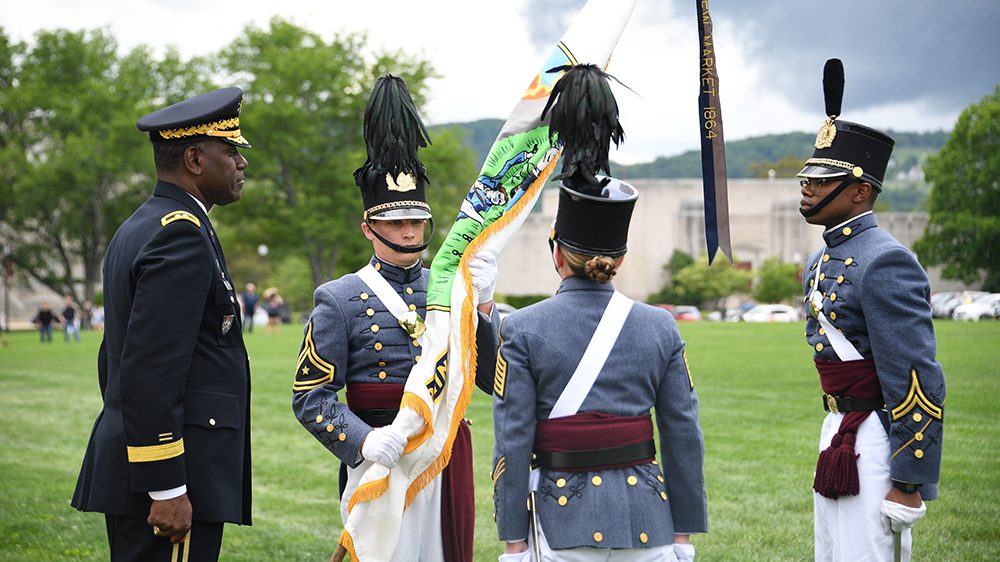 Three cadets and Maj. Gen. Wins stand on Parade Ground, as two cadets participate in the change of command ceremony, handing off the colors
