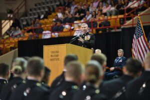 Gen. Eric M. Smith offers remarks and administers the oath for graduating cadets commissioning into the U.S. Marine Corps as be stands behind podium in Cameron Hall.