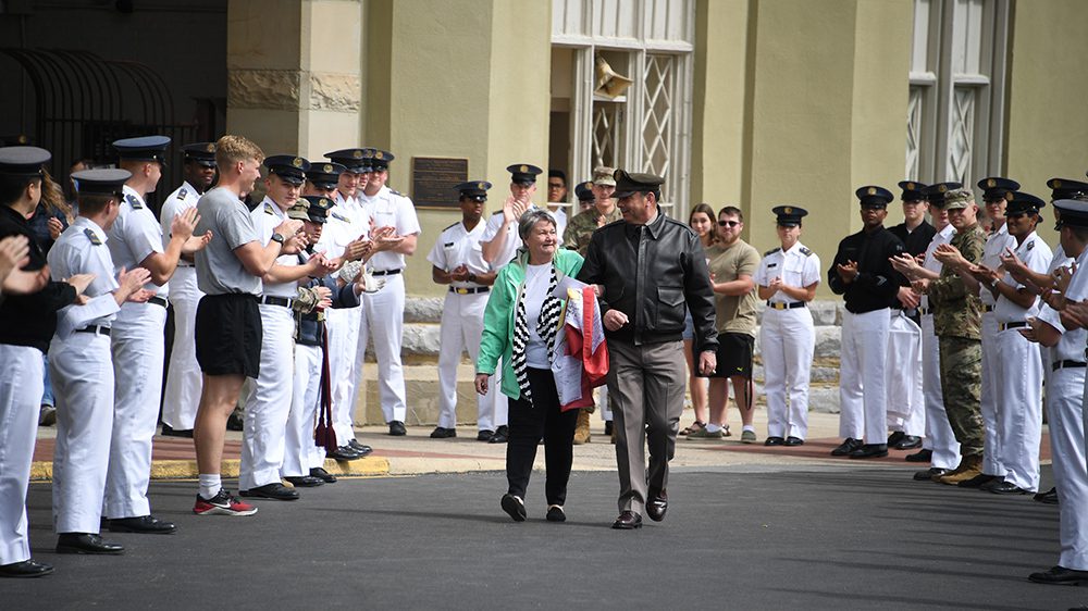 Col. Adrian T. Bogart III ’81, commandant, escorts Vergie Moore as cadets form a cordon to honor her after five decades of service at VMI.