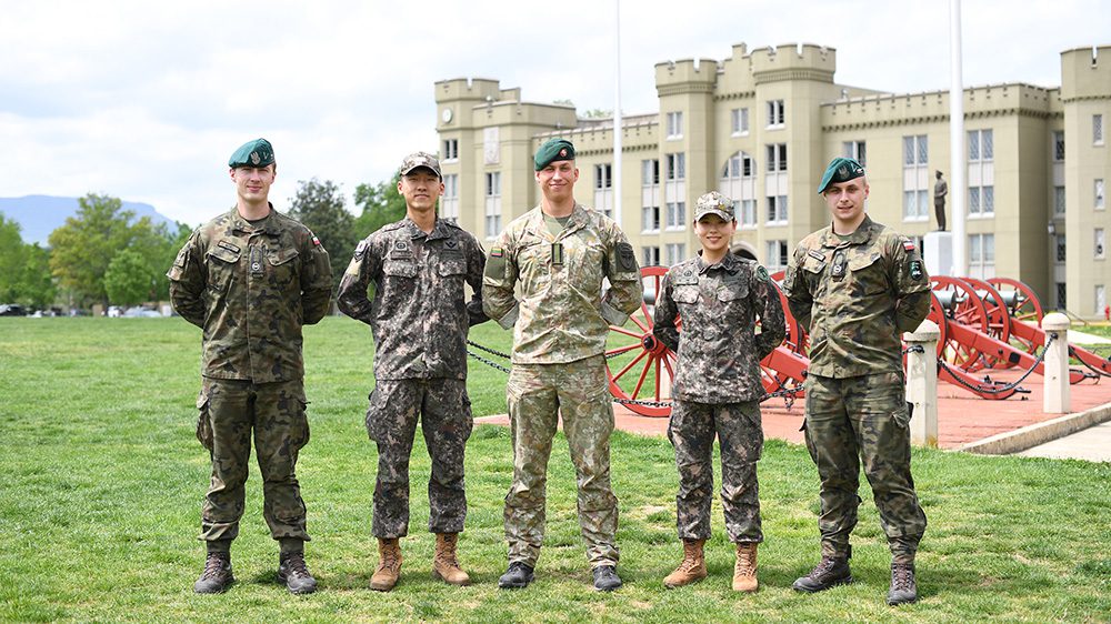 Five cadets pose on parade ground with hands behind back.