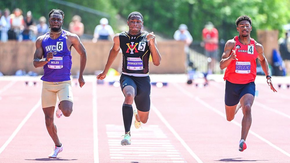 Three track athletes running on outdoor track.