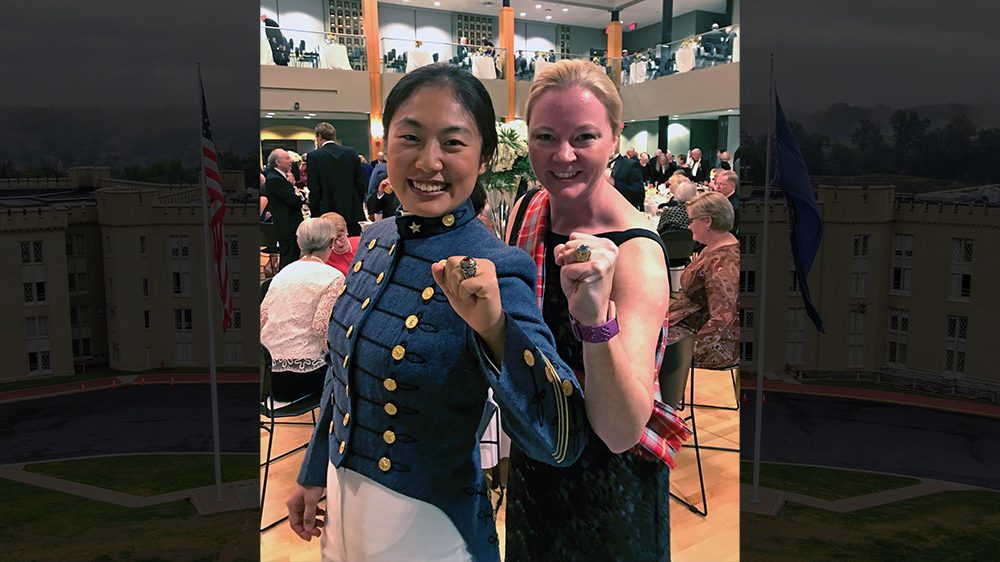 alumna and cadet smile and hold up class rings