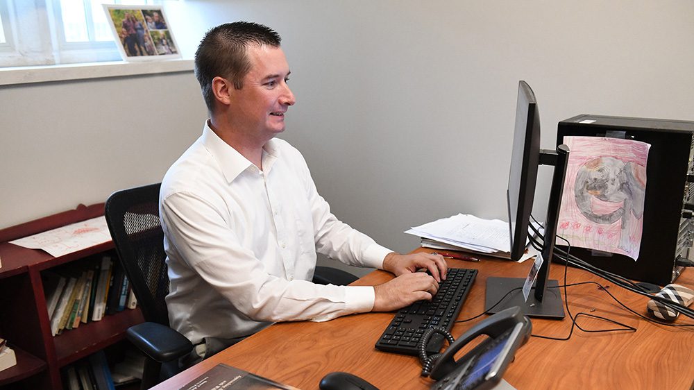 Man smiling as he types on desktop computer