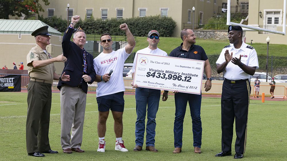 members of Class of 2012 present reunion check on football field