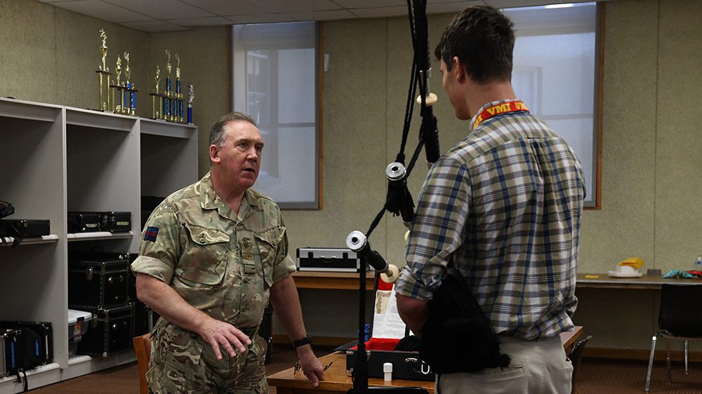 Maj. Brian Donaldson, new pipe band director, discusses the bagpipes with a high school student