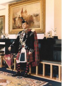 Maj. Brian Donaldson poses in his full bagpipe dress complete with kilt, plaid, and feather bonnet as pipe major in Scotland