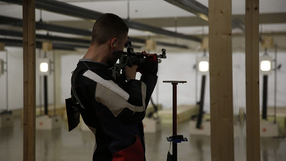 Rifle team member aiming rifle at target