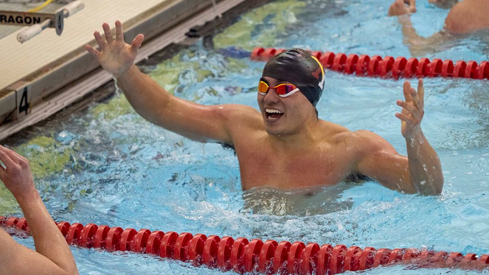 swimmer in pool smiling with arms in the air