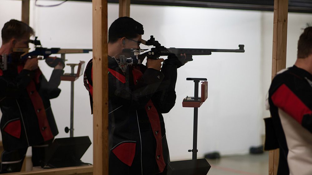 rifle team member aiming rifle at target