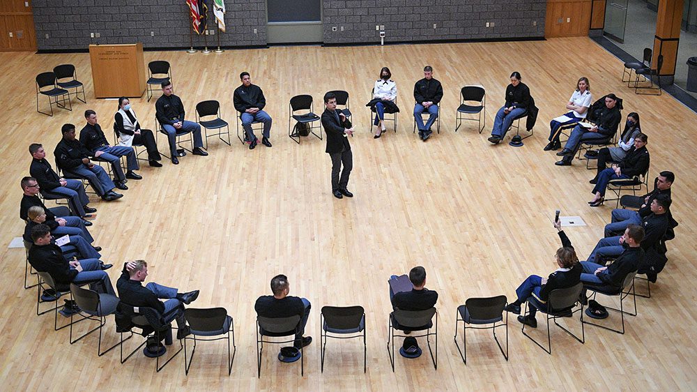 cadets seated in a circle with moderator standing in the center