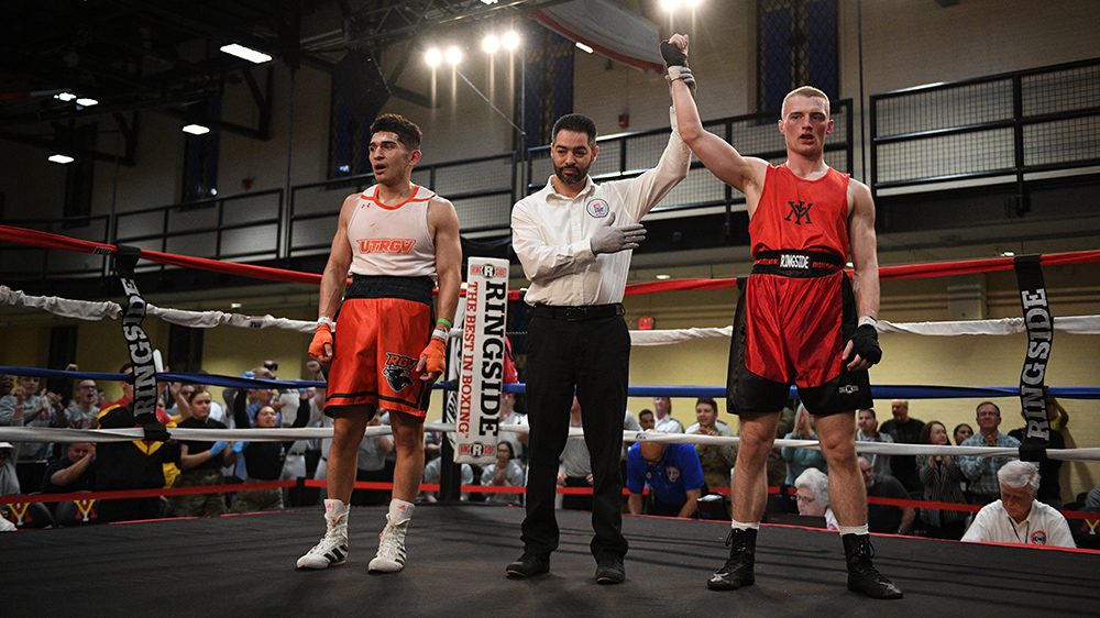 referee holding up hand of VMI boxer, declaring him the winner