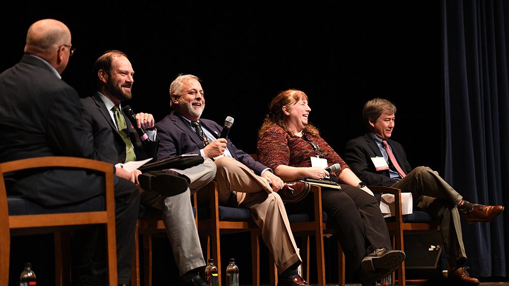 panel of individuals seated on stage speaking