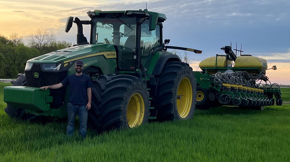 Thomas Louderback ’11 standing next to tractor