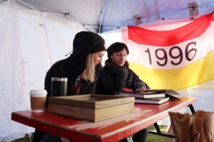 Rachel Edge (left) and Helena Edge, daughters of James C. “Jamie” Edge ’96, examine memorabilia from their father’s cadetship