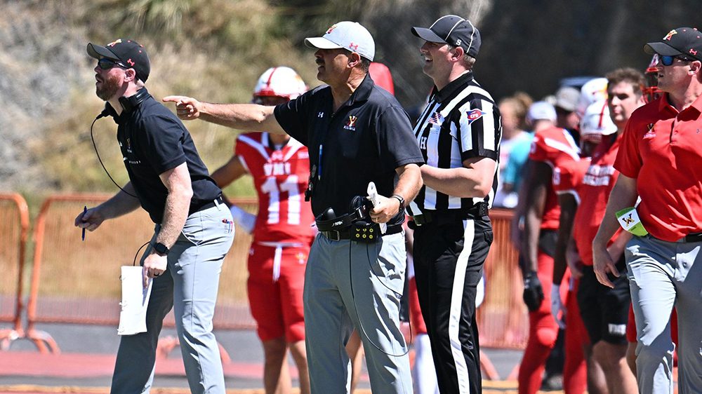 Coach Danny Rocco and coaching staff and referee on football sideline