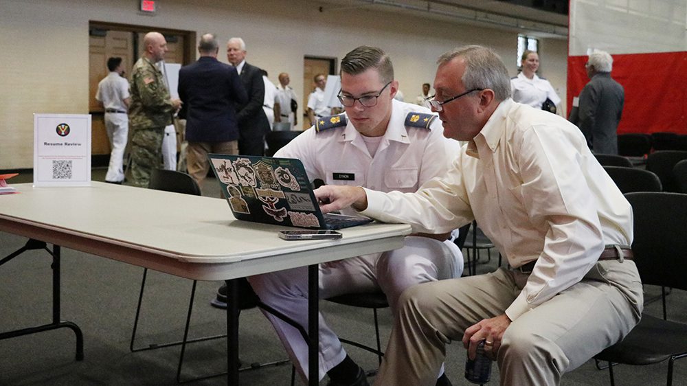 cadet and alumnus looking at laptop screen together