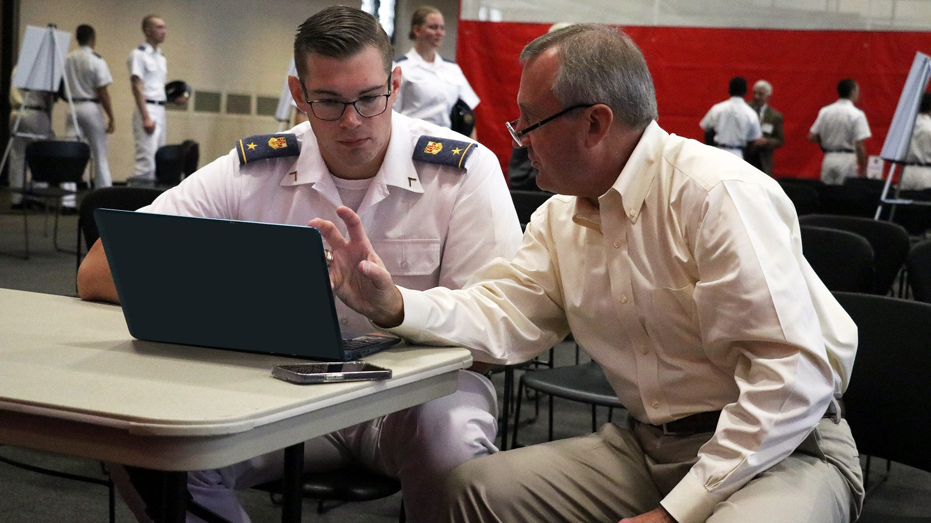 Alumnus talking with cadet at laptop