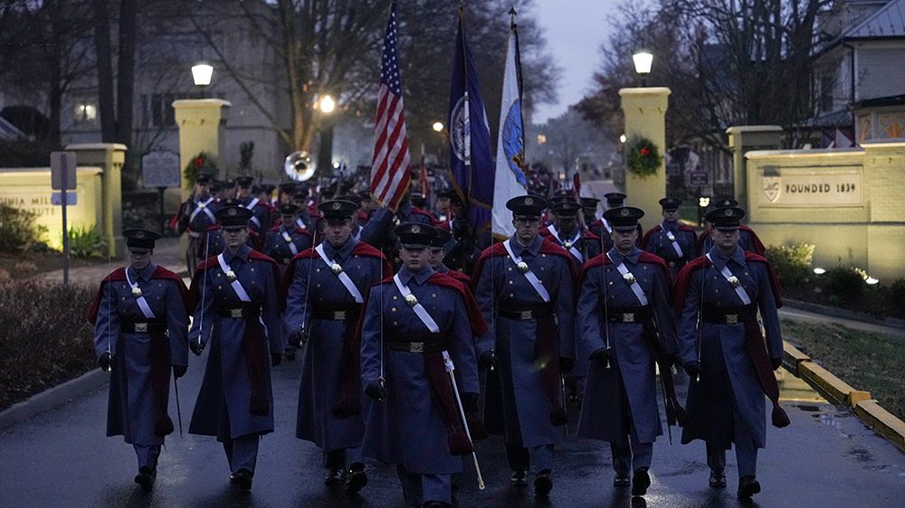 cadets in gray uniforms and red capes march down Letcher Ave