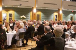 guests seated at round dining tables, clapping