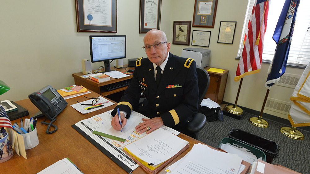 Brig. Gen. Robert L. Green ’67 seated behind desk, writing on notepad