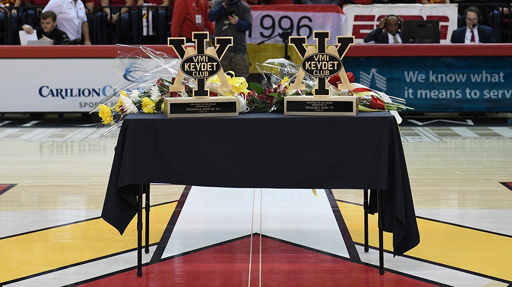 table at center of basketball court with Spirit of VMI Awards and flowers on top