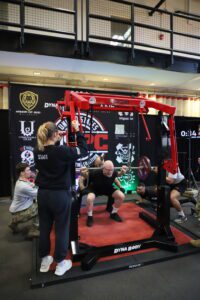 Man lifts barbell while others spot him