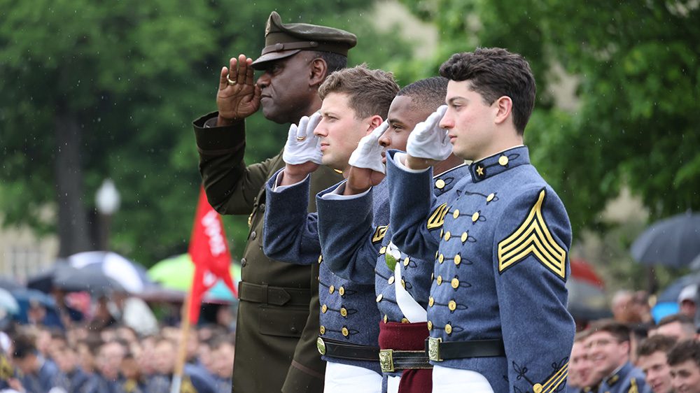 Three cadets and the superintendent saluting