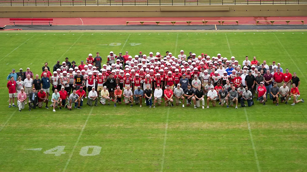 football team and alumni gathered for photo on football field