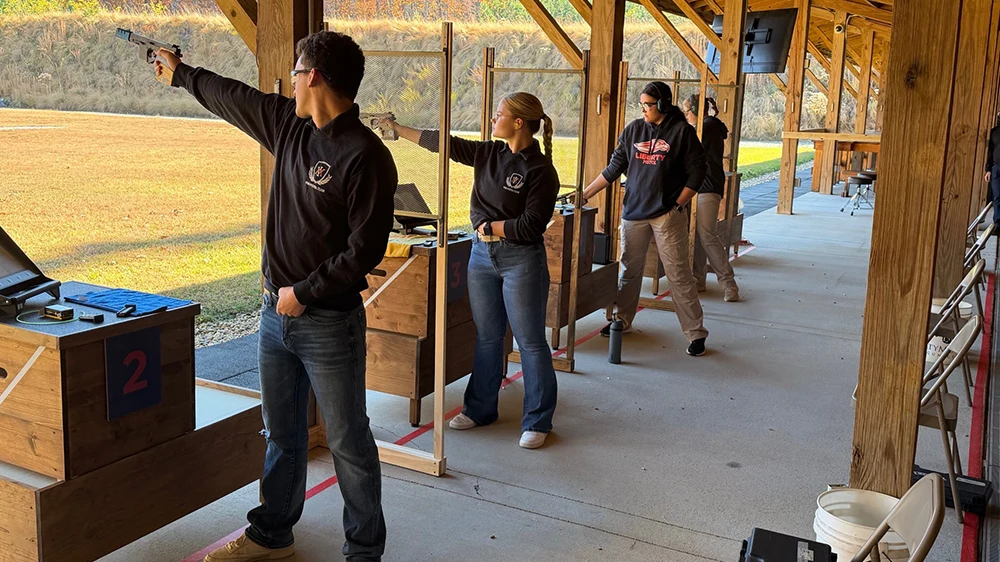 three people aiming pistols at targets