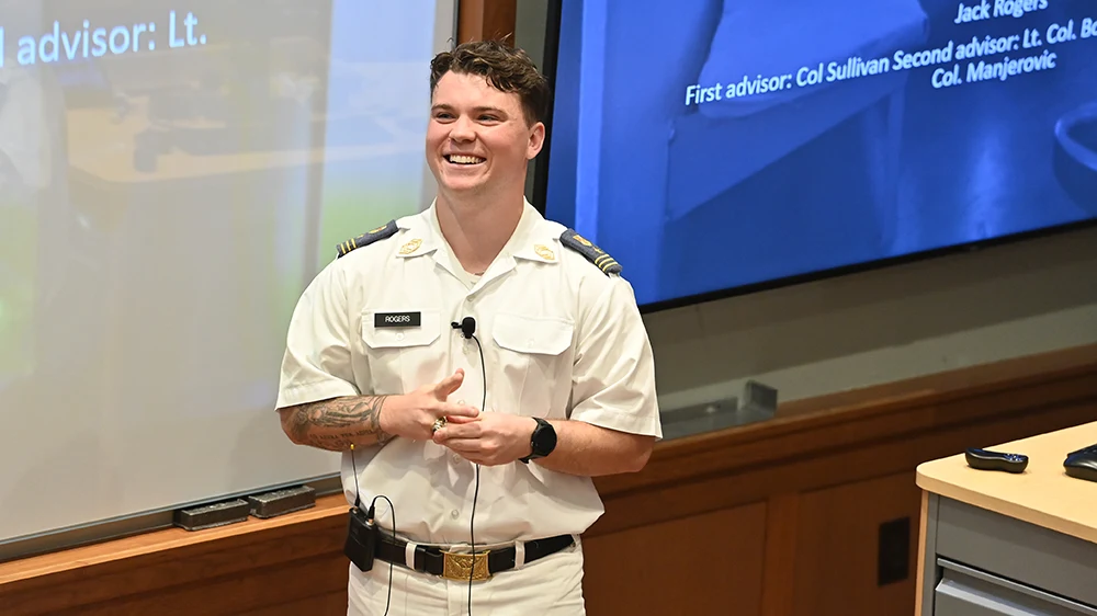 cadet standing in front of projection screen mid-presentation, smiling