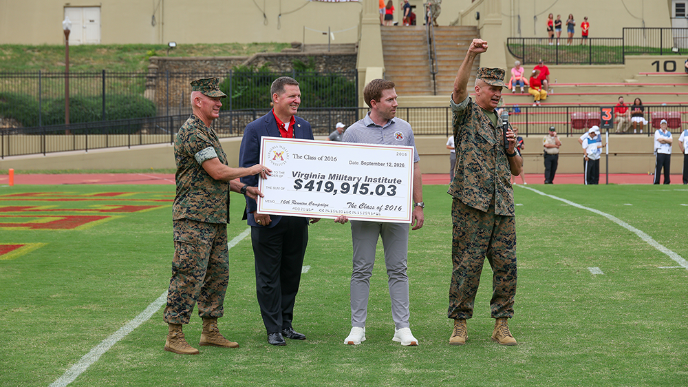The Class of 2016 presents its 10th Reunion gift of $419,915.03 to the Institute on football field. Pictured are Sgt. Maj. Tom Sowers, Institute and Corps sergeant major; Dallas Clark ’99, VMI Alumni Agencies chief executive officer; Murphy Kerner ’16, class agent; and Lt. Gen. David Furness ’87, superintendent.