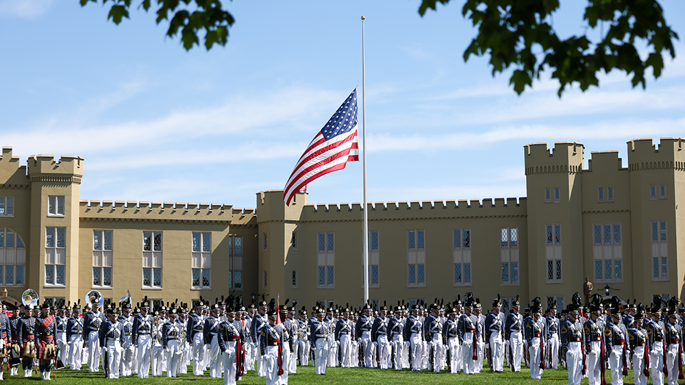 Corps of Cadets in parade formation, parade flag at half staff in background